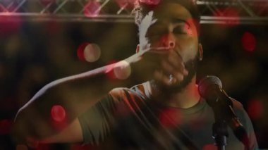 Müzik sanatçısı kadehini kaldırıp sahnede yudumluyor. Renkli mercek fişekleri, kirişler var. Performans, gece hayatı, atmosfer, eğlence, sinematik, canlı, kutlama