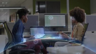 Modern işletme masasında dizüstü bilgisayardaki çizelgeleri inceleyen iki kadın yüzen veri grafikleri gösteriyor. İşbirliği, takım çalışması, teknoloji, üretkenlik, yenilik, iletişim, profesyonel