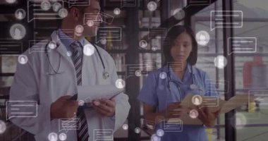 Doktor ve hemşire klinik koridorundaki tıbbi raporları inceliyor, yüzen sohbet simgelerini gösteriyor. İşbirliği, sağlık, iletişim, modern, profesyonellik, takım çalışması, tıbbi