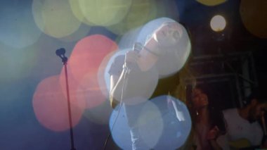 Kadın şarkıcı mikrofon tutuyor ve müzik sahnesinde renkli bokeh ışıklarıyla şarkı söylüyor. Sanatçı, eğlence, canlı müzik, performans, konser, sahne sanatları, atmosfer