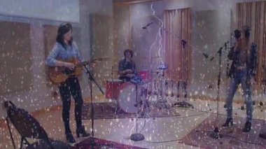 Üç müzisyen stüdyoda prova yapıyor, gitar, davul seti, mikrofon, kar yağışı örtüsü. Yaratıcı, işbirliği, ses geçirmez, uyum, kayıt, profesyonel, akustik