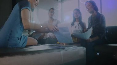 Kadın işbirlikçi, iş verileriyle dolu salondaki ekibe dokümanları teslim etmek için öne eğiliyor. İşbirliği, takım çalışması, yenilik, teknoloji, modern, gelecekçi, iletişim