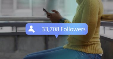 Ulaşım merkezinde akıllı telefonu kontrol eden kadın sosyal medya takipçileri simgesi sergiliyor. Kentsel, teknoloji, gelişigüzel, iletişim, modern, canlı, sosyal