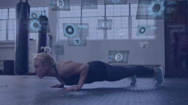 Kadın spor salonunda lastik paspasın üzerinde şınav çekiyor dairesel veri grafikleri ve kod akışları gösteriyor. Fitness, teknoloji, eğitim, güç, yenilik, spor salonu, modern