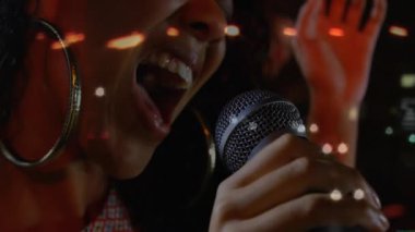 Müzik sahnesinde mikrofon tutan kadın şarkıcı, animasyon notaları ve ses dalgası grafikleriyle. Performans, eğlence, dinamik, canlı, duygu, spot ışığı, sanatsal