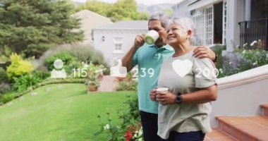 Arka bahçede kupa tutan yaşlı bir çift, sağlık verileri ve kalp ikonu gösteriyor. Aile, rahatlama, yaşam tarzı, açık hava, sükunet, ahenk, refah
