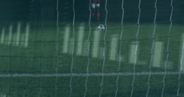 Erkek futbolcu kalede elinde spor analitik bar grafikleri ve dalga boylarını gösteren bir topla duruyor. Atletik, rekabetçi, dijital, modern, performans, açık hava, aktif