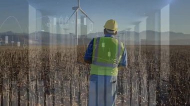 Saha mühendisi sert şapka ve güvenlik yeleği giyiyor rüzgar türbinlerini inceliyor, finans tabloları sergiliyor. Yenilenebilir, sürdürülebilirlik, teknoloji, açık hava, endüstri, yenilik, ilerleme