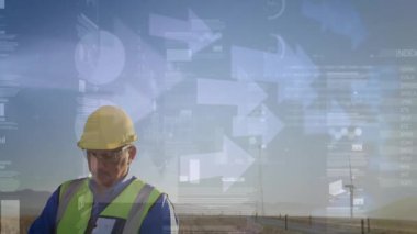 Saha teknisyeni rüzgar tarlasında tablet kullanıyor. Enerji verilerini animasyon çizelgeleri ve oklarla izliyor. Sanayi, teknoloji, fütürizm, yenilenebilir, sürdürülebilirlik, açık hava, yenilik