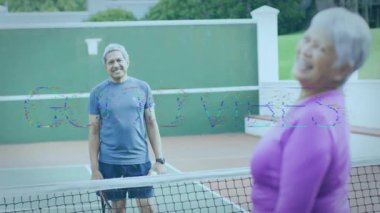 Açık tenis kortunda oynayan yaşlı çift raket ve topun üstünde animasyon sağlık grafikleri gösteriyor. Atletik, arkadaşlık, zindelik, açık hava, boş zaman, aktivite kıyafeti, sportmenlik.