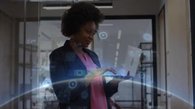 Ofiste elinde dizüstü bilgisayarla duran profesyonel bir kadın holografik finans veri tabloları gösteriyor. Teknoloji, yenilik, veri, dijital, kurumsal, modern, çalışma alanı