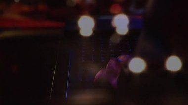 Erkek müzisyen canlı sahnede klavye kontrollerini animasyon ışık ve ses dalgası grafikleriyle ayarlıyor. Konser, sahne, ışıklandırma, sanatçı, müzik, performans, ambians