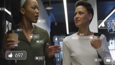 İki meslektaş ofis koridorunda yürüyor, pazarlama için yüzen sosyal medya simgeleri gösteriyorlar. Profesyonel, işbirliği, modern, kentsel, ağ, teknoloji, tarz