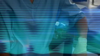 Orta yaşlı bir sağlık çalışanı, deniz mavisi önlük giyip klinikte hayati organları tarıyor ve yüzen mavi çizgiler çiziyor. Tıbbi, profesyonellik, temiz, steril, teknoloji, sağlık hizmetleri, hastane