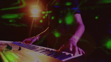 Sahnede klavye çalan bir adam, neon çizgileri ve işaret fişekleri olan müzik teknolojisi sergiliyor. Müzik, performans, konser, gece hayatı, eğlence, sanatsal, canlı