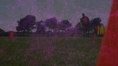 Altı takım arkadaşı çimen sahasında futbol talimi yapıyor, spor teknolojilerini mor ağ örtüleri ile kullanıyorlar. Atletizm, fitness, antrenman, hareket, takım çalışması, açık hava, canlı