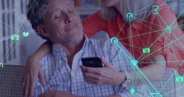 Üst düzey çift akıllı telefon kullanarak kanepede oturuyor. Teknolojik bağlantı simgeleri ve Wifi sembolleri gösteriyorlar. Yaşlılar, teknoloji, bağlantı, arkadaşlık, rahatlama, modern, dijital