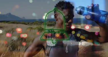 Atletik adam, kıyı kum tepelerine şişeden su dökerek, sağlık için neon uyarı ikonu gösteriyor. Aktif giysi, hidrasyon, açık hava, macera, doğa, canlılık, tazelik