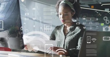 Teknoloji ofisindeki belgeleri inceleyen, yüzen çizelgeler ve arayüz simgeleriyle etkileşim içinde olan bir kadın. Profesyonel, yenilik, veri, analitik, çalışma alanı, dijital, modern