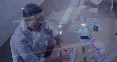 Tasarım stüdyosunun masasında yazı yazan olgun bir adam yüzen grafikleri renk çarkını gösteriyor. Profesyonel, çalışma alanı, modern, yaratıcı, analitik, dijital, yenilik