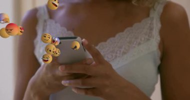 Stüdyoda akıllı telefon kullanan bayan pazarlamacı sosyal medya için yüzen üç boyutlu emoji kürelerini izliyor. Teknoloji, iletişim, eğlence, dijital, yenilik, ifade, modern