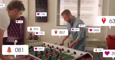 Ofis içinde langırt oynayan iki adam, pazarlama için yüzen sosyal medya simgeleri sergiliyorlar. Eğlence, işbirliği, eğlence, modern, canlı, etkileşim, ofis