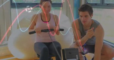 Spor hocası kürek çekme makinesinde müşteri çalıştırıyor, kalp atış hızı grafiği ve zamanlayıcı gösteriyor. Atletik, sağlık, motivasyon, güç, modern, sağlık, eğitim