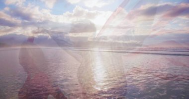 Sahilde Amerikan bayrağı taşıyan beyaz bir çiftin üzerinde okyanus manzarası. Okyanus günü ve dijital olarak üretilen görüntü konsepti.