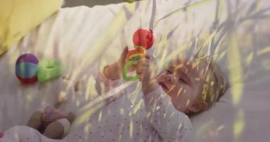 Anne kucağında çıngıraklı bebekle yatak odasında çıngırak tutuyor, çimen kaplamalı sağlık bilgilerini gösteriyor. Bebek gibi, şefkatli, yürekten, evcil, masum, şefkatli, rahat