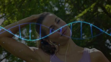 Parkta boynunu uzatan, kulaklıkla dinleyen, biyoteknoloji DNA sarmalı gösteren bir kadın. Fitness, wellness, natural, futuristic, viviviality, technology, outdoor