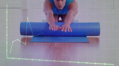 Adam yoga minderinde köpük paten arkasında diz çöküp neon yeşil Cyan dijital grafiğiyle fitness izliyor. Fitness, health, training, digital, technology, modern, lifestyle