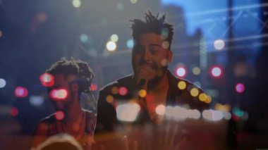 Baş solist mikrofona şarkı söylüyor, geri vokalist Bokeh ışıkları eşliğinde müzik eşliğinde uyum sağlıyor. Canlı müzik, konser, sahne, performans, şehir, gece hayatı, kutlama