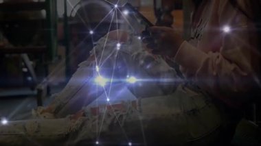 Depo zemininde akıllı telefon kullanan bir kadın. Parlak teknoloji bağlantısını gösteriyor. Teknoloji, ağ oluşturma, bağlantı, kentsel, modern, dijital, yenilik