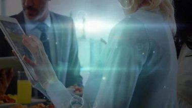 Meslektaşı izlerken kadın tablet ekranına tıklıyor, yüzen iş çizelgeleri ve grafikler gösteriyor. Teknoloji, yenilik, işbirliği, dijital, veri, iletişim, geleceksel