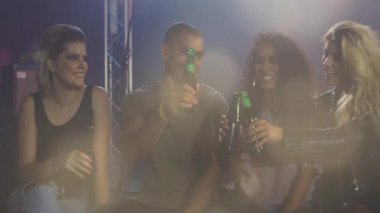 Müzik notaları eşliğinde kulüp eğlence sahnesinde yeşil şişe kaldıran bir grup arkadaş. Kutlama, yoldaşlık, gece hayatı, canlı, sosyal, enerjik, eğlence