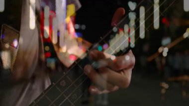 Erkek müzisyen, müzik eğitimini gösteren animasyon notaları eşliğinde neon ışıkların altında gitar çalıyor. Gitar, gece hayatı, sokak sanatçısı, müzik, şehir, gösteri, atmosfer