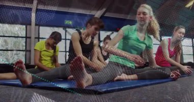 Bir grup kadın spor salonundaki mavi minderlerin üzerinde hareketli grafikler sergiliyor. Spor, sağlık, esneklik, eğitim, sağlık, egzersiz, canlılık