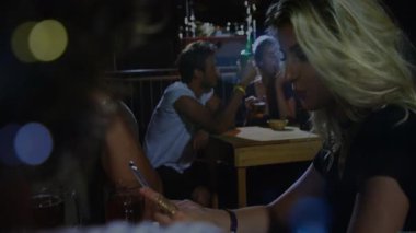 Arkadaşlar verandada mikrofon ve sohbet baloncuklarıyla teknoloji gösteren akıllı telefonlar kullanıyorlar. Sosyalleşme, gece hayatı, ambiyans, eğlence, eğlence, gündelik, kentsel