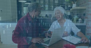 Mutfakta dizüstü bilgisayar kullanan yaşlı bir kadın ve olgun bir adam. İçinde yüzen finansal tablolar ve veriler var. Mali planlama, işbirliği, modern dekor, dijital teknoloji, konforlu ev, nesiller arası, takım çalışması