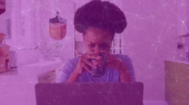 Mutfakta uzaktan kumandalı bir kupa tutan bir kadın. Animasyon çizelgeleri olan bir laptop kullanıyor. Çağdaş, rahat, yaşam tarzı, üretkenlik, iç mekan, canlı, rahat