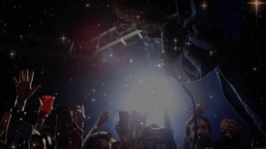 Sanatçı mikrofon tutuyor ve müzik endüstrisinde fanlar canlı ses dalgalarıyla telefonları kaldırıyor. Konser, seyirci, sahne, ışıklandırma, performans, gece hayatı, canlılık