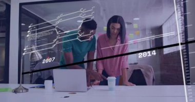 Teknoloji ofisindeki masaya yaslanmış iki profesyonel kod ve veri tablolarını inceliyor. İşbirliği, takım çalışması, yenilik, modernizasyon, analitik, dijital, ofis