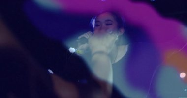 Sahnede performans sergileyen bayan şarkıcı, teknoloji ses dalgaları ve neon ışıklı merceklerle. Performans, konser, gece hayatı, canlı, eğlence, atmosfer, sahne