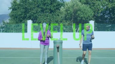 Son sınıf çifti raketlerle tenis oynuyor açık hava sağlık sahnesinde yüzen LEVEL Up yazıları var. Atletizm, spor, spor, spor, eğlence, spor, etkinlik