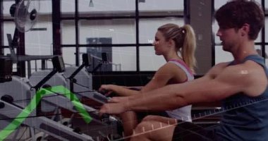 Spor partnerleri spor salonundaki kürek makinelerini kullanarak yeşil performans grafiklerini gösteriyorlar. Fitness, antrenman, egzersiz, güç, dayanıklılık, kardiyo, sağlık