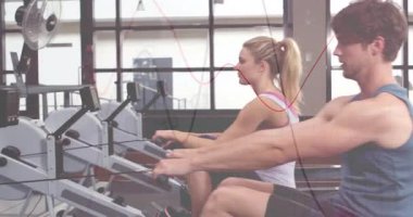 Spor salonunda kürek çeken iki sporcu dijital monitörlerde animasyon performans grafikleri gösteriyor. Atletik, takım çalışması, modern, işlevsel, motivasyon, eğitim, sağlıklı