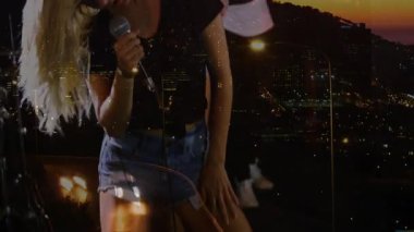 Solist yan yatmış mikrofonu kavrayıp, müzik temasını şehrin ışıklarıyla örtüyor. Müzisyenler, performans, gece hayatı, sahne, ritim, melodi, eğlence