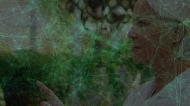 Yapraklı parkta ileri bakan kıdemli bir kadın dijital ağ hatlarının parlayan düğümler teknolojisini gösteriyor. Açık hava, teknoloji, bağlantı, kıdemli, doğa, dijital, yenilik