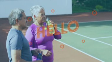 Elinde su şişeleri olan ve tenis kortunda konuşan bir çift. Spor reklamı için de Hello. Sporcular, sağlık, aktif yaşam tarzı, spor giyimi, motivasyon, canlılık, açık hava eğlencesi