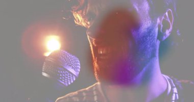 Müzik endüstrisi sahnesinde canlı ses dalgaları ve parıldayan veri grafikleriyle performans sergileyen erkek şarkıcı. Performans, vokaller, sahne, konser, ışıklandırma, müzik, sanatçı